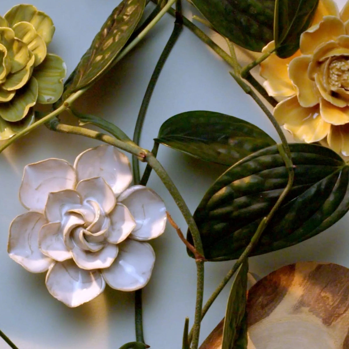 Ivory daffodil ceramic wall flower surrounded by jade green and fir green English Garden ceramic flowers on white background — handmade by Chive Studio Toronto
