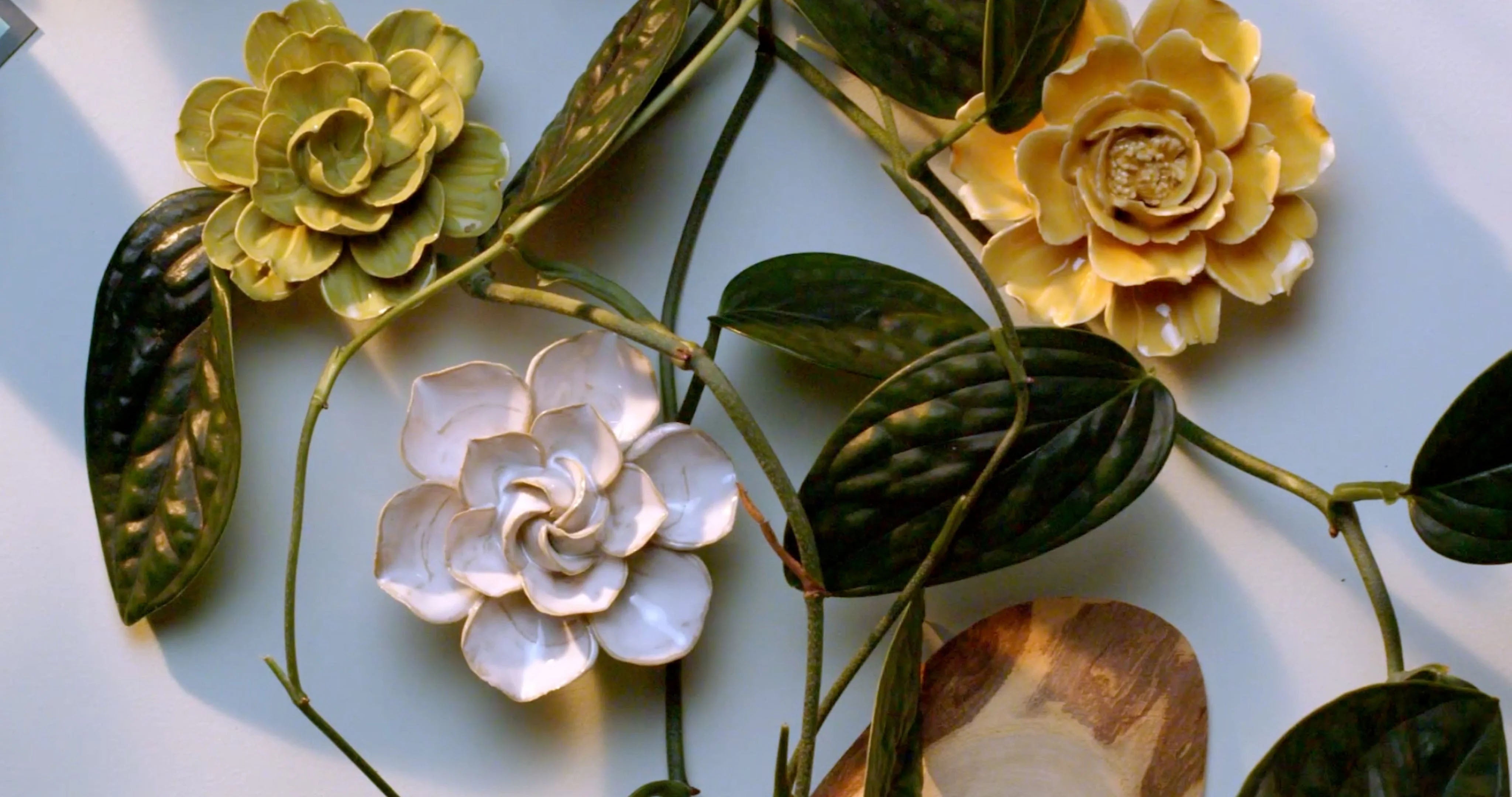 Ivory daffodil ceramic wall flower surrounded by jade green and fir green English Garden ceramic flowers on white background — handmade by Chive Studio Toronto