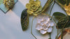 Ivory daffodil, burnt yellow rose and chartreuse primrose ceramic wall flowers styled with seed packets, flower stems and raw oak wood — top down pan — English Garden Collection — Chive Studio