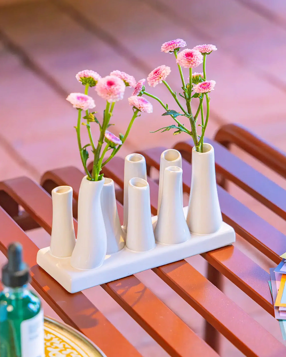 Chive ceramic pooley bud vase in color white, styled with fresh flowers, on a table.